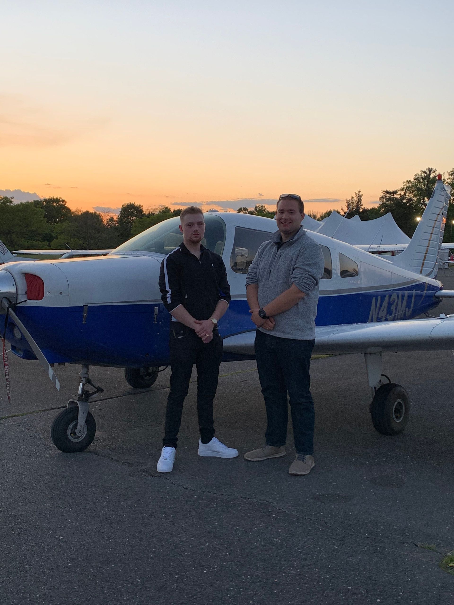 two men are standing in front of a small plane