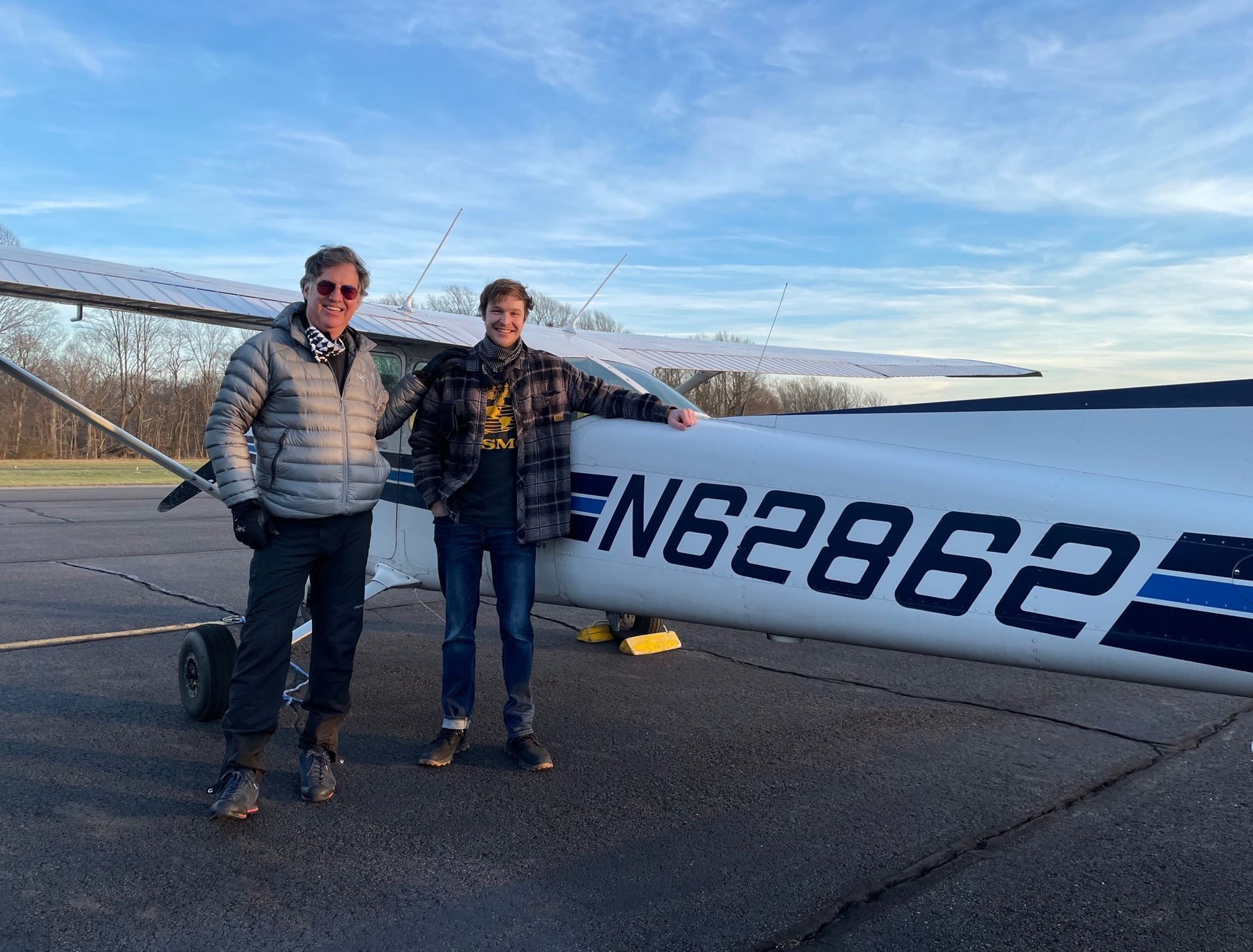 two men are standing in front of a small plane