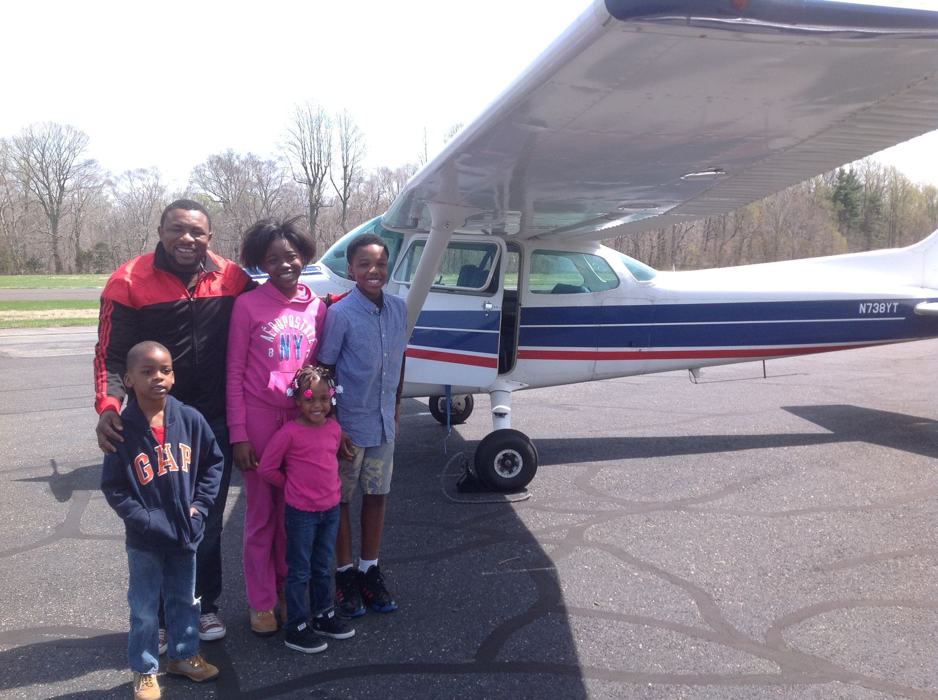 a family standing in front of a small plane that says gap on it