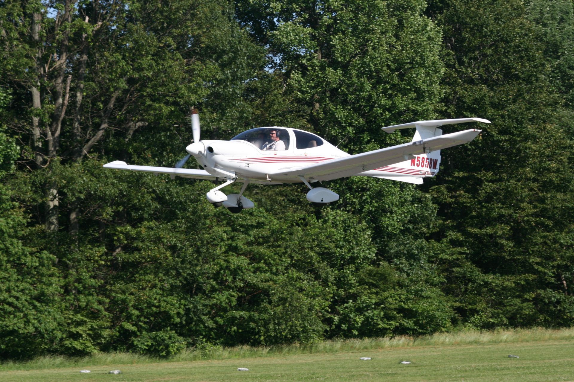 a small plane is flying over a field with trees in the background