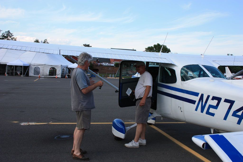 two men are standing next to a plane with the number n274 on it