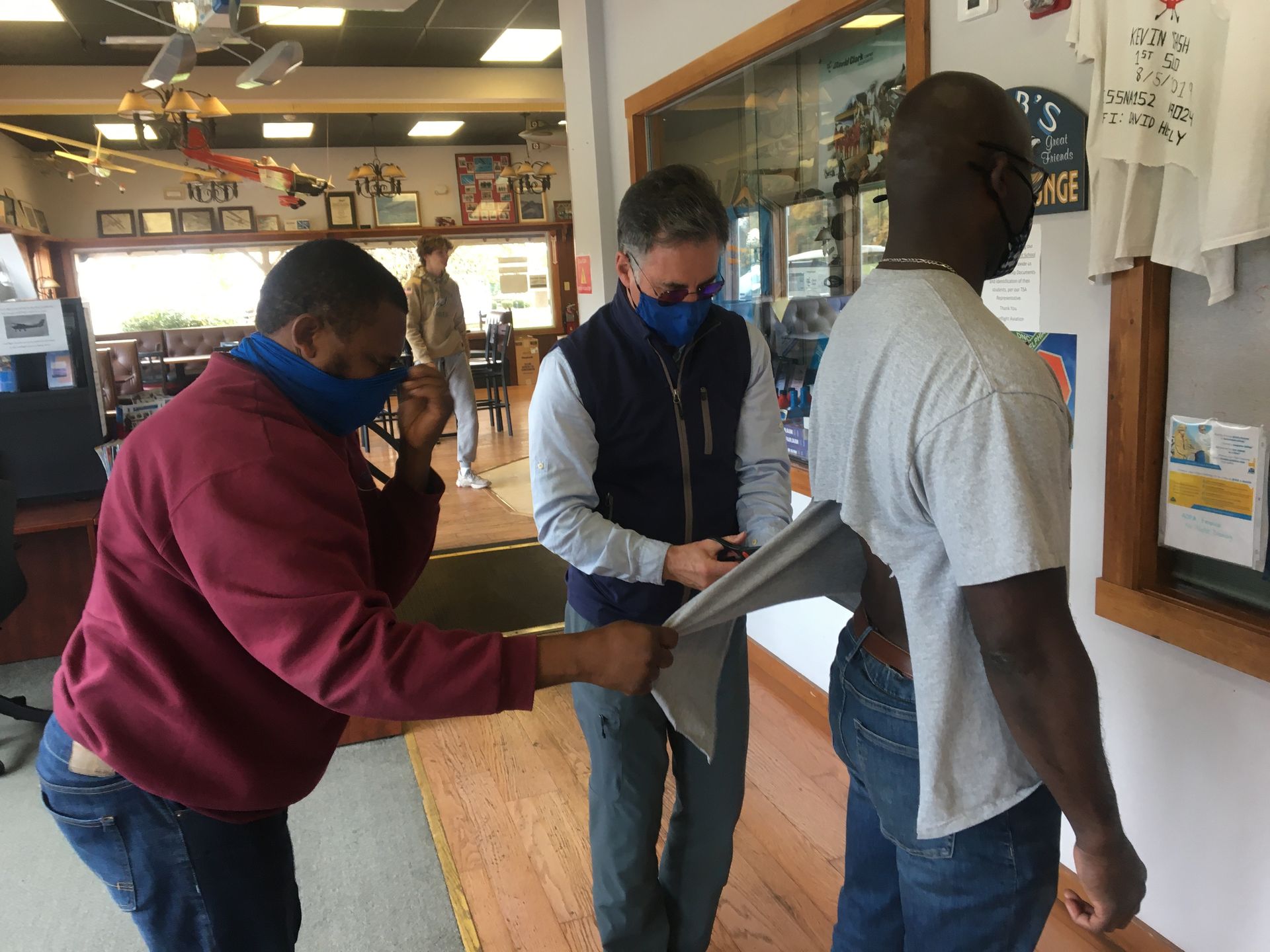 three men wearing face masks are standing in a room