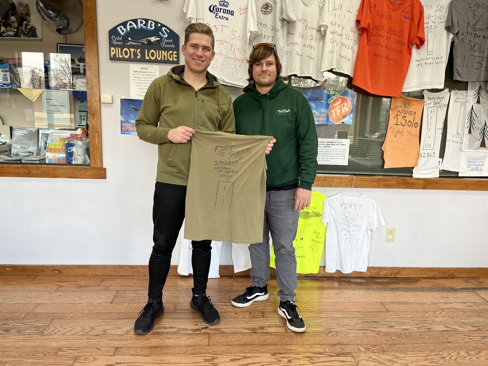 two men are standing next to each other holding a t-shirt in a store