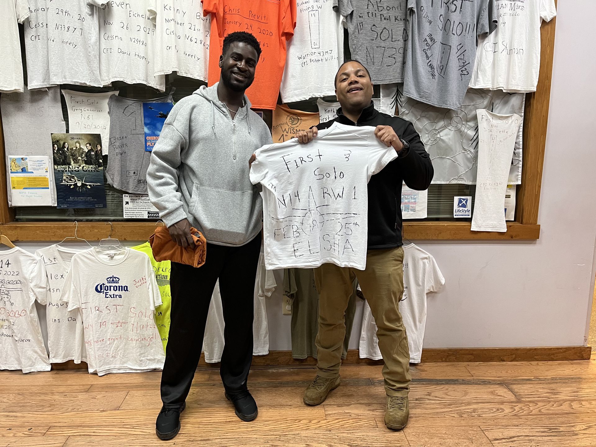 two men are standing next to each other in a store holding t-shirts