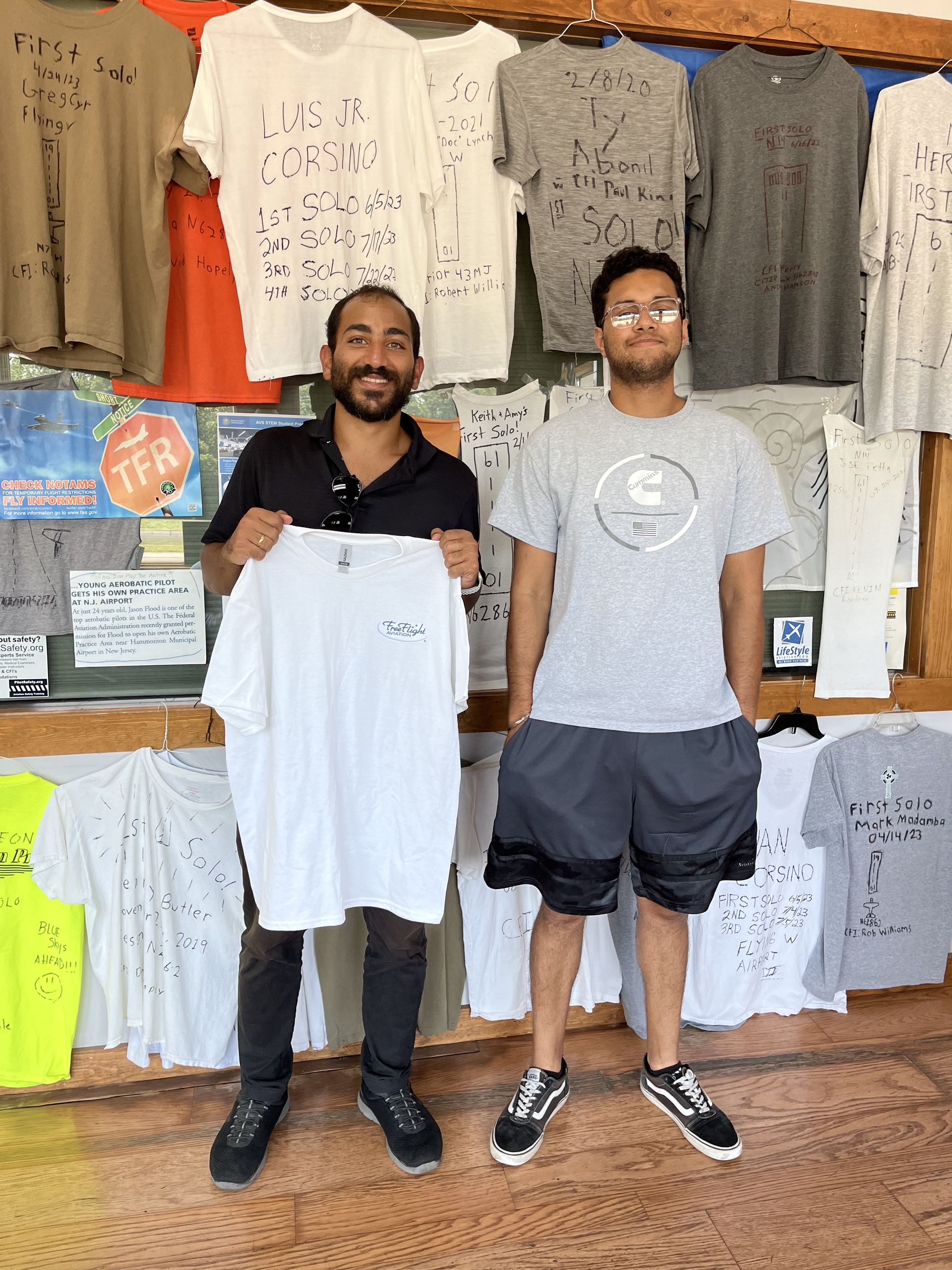 two men are standing in front of a display of shirts