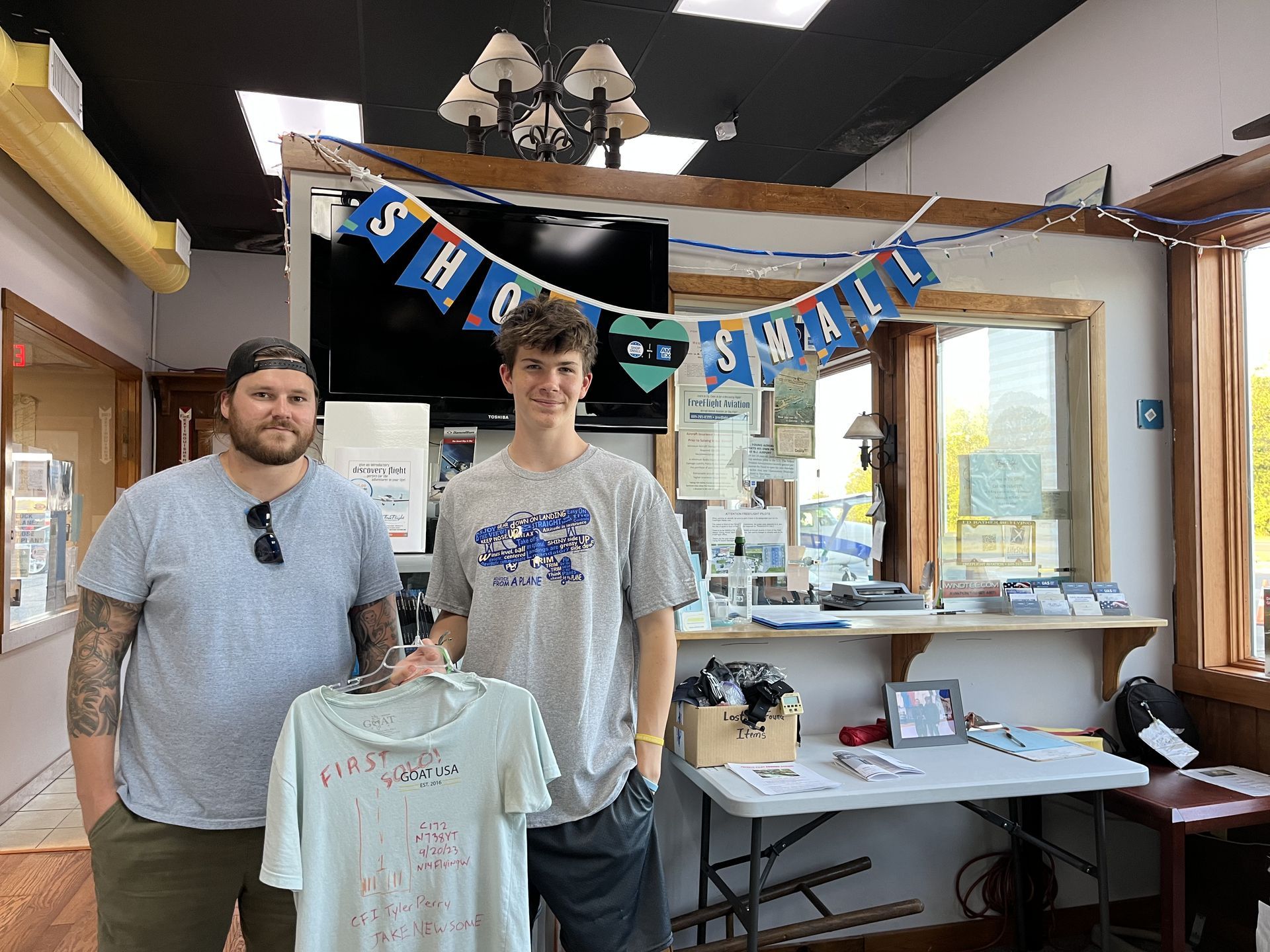 two men are standing next to each other in a room holding a t-shirt