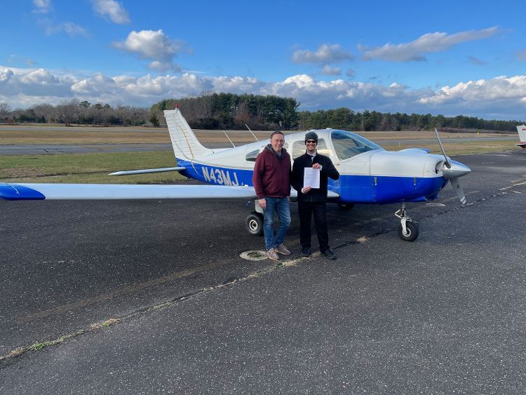 two men are standing in front of a small plane on a runway