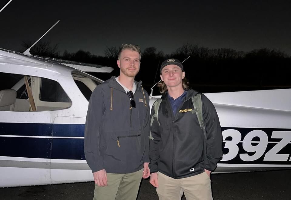 two men standing in front of a plane with the number 397 on it