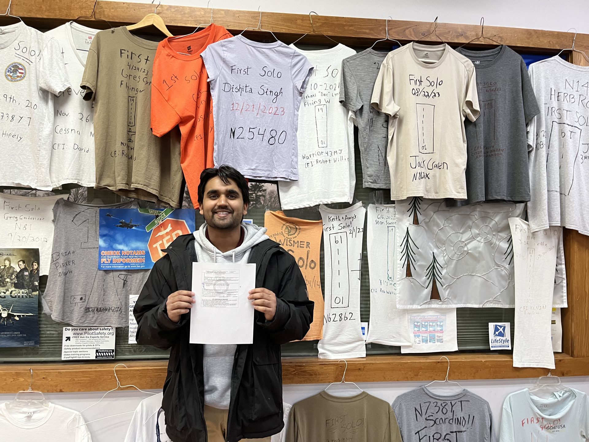 a man holding a piece of paper in front of a wall of shirts
