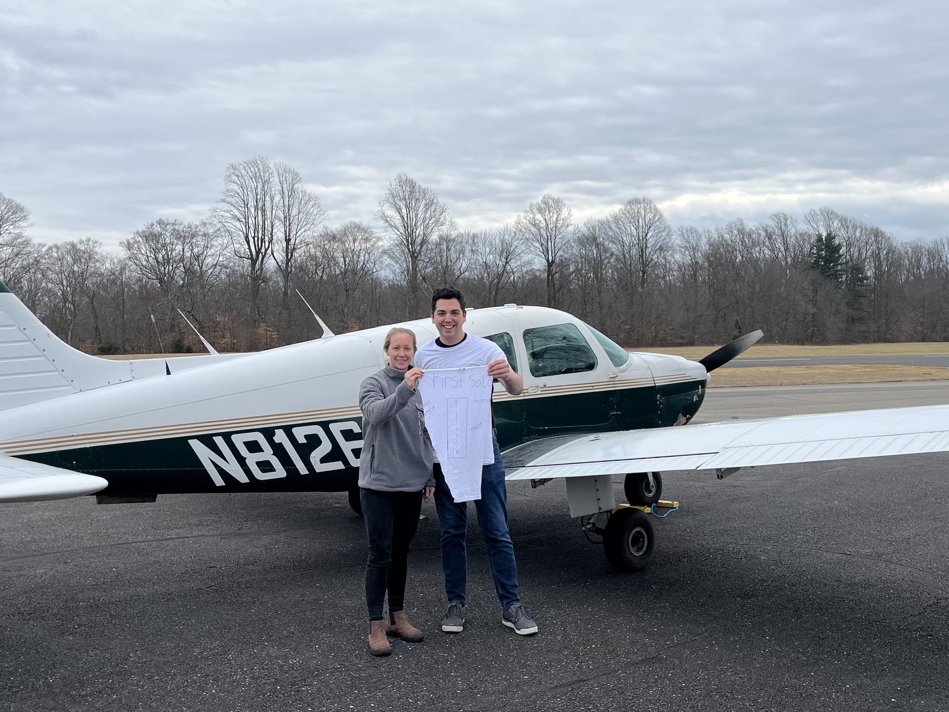 a man and a woman are standing in front of a small plane