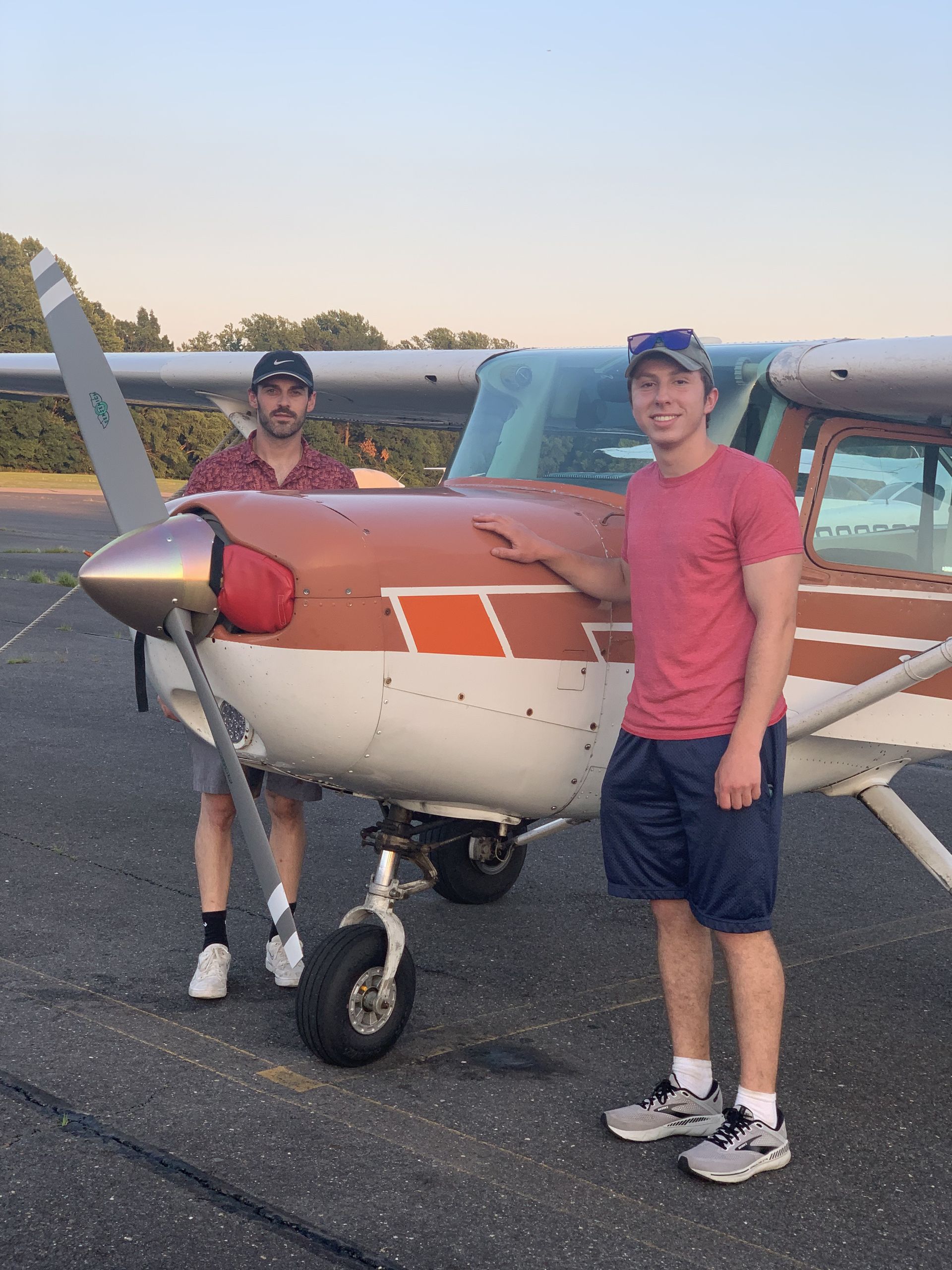 two men are standing in front of a small plane