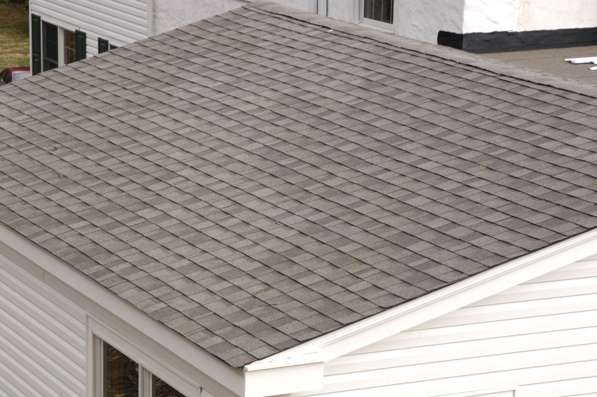 Gray shingled roof on a white house, viewed from above