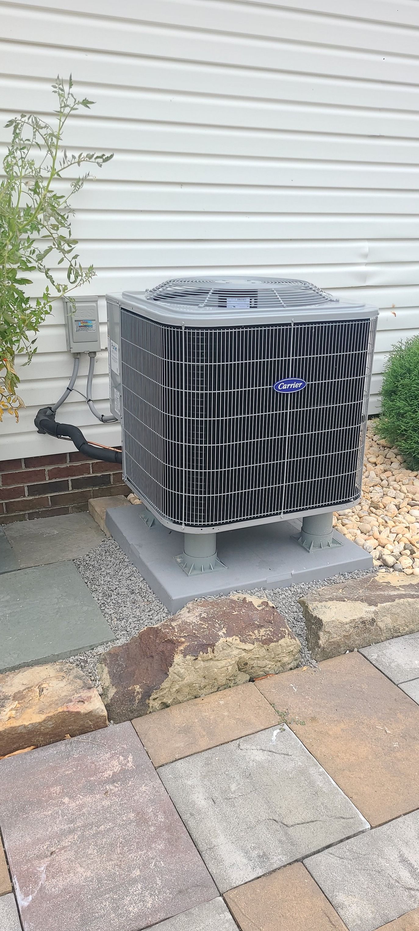 An outdoor air conditioning unit on a concrete pad near a house.