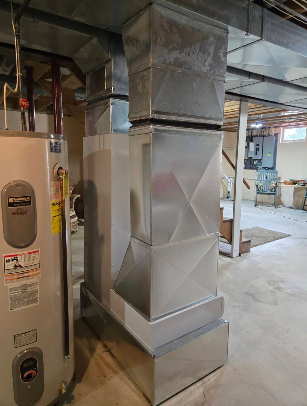 Metal HVAC ductwork in a basement next to a water heater.