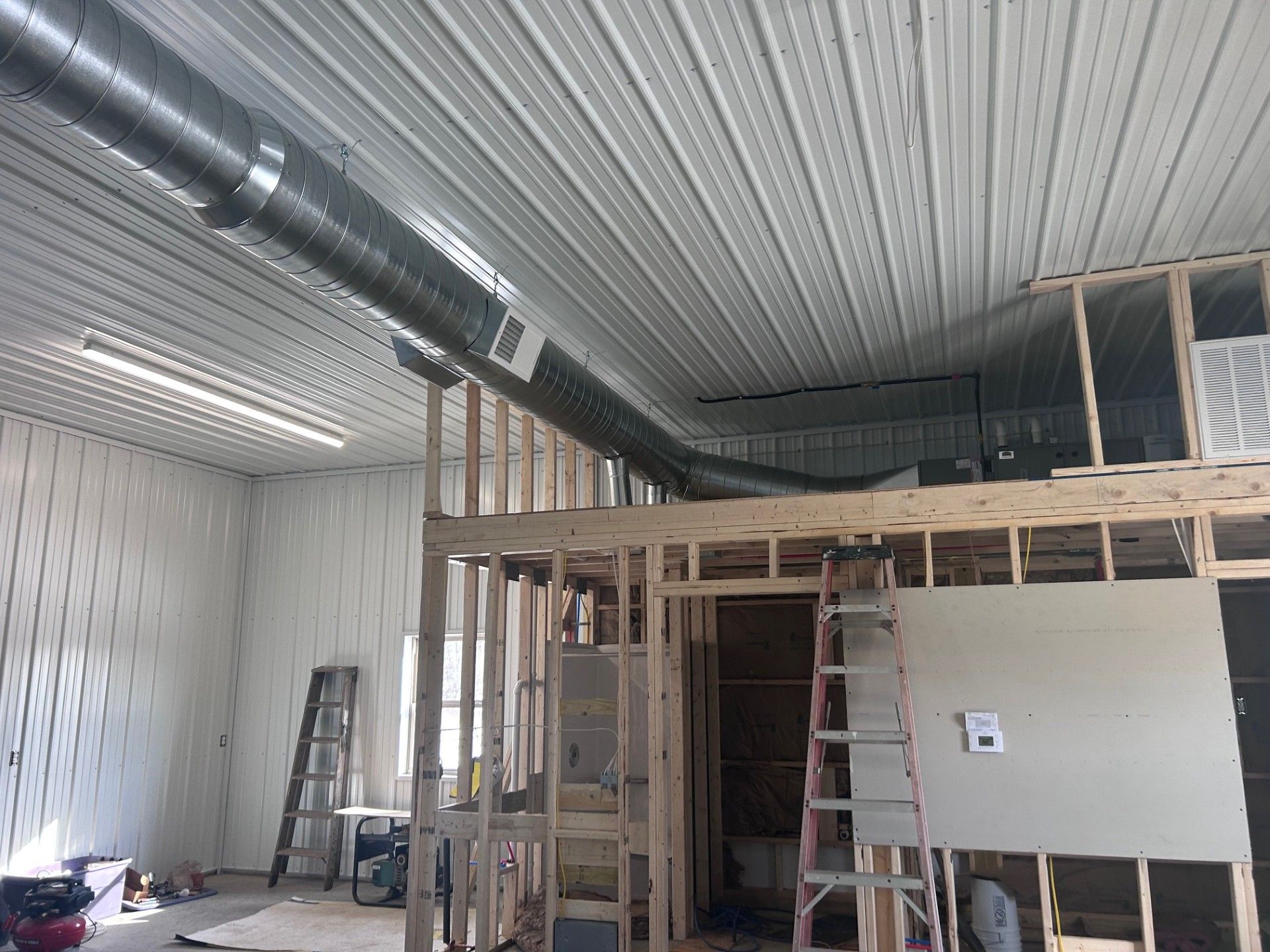 Interior view of a building under construction, showing HVAC ductwork and exposed framing.