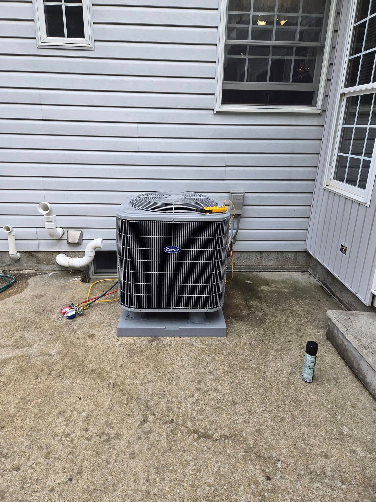 Air conditioning unit outside a house, on a concrete pad.