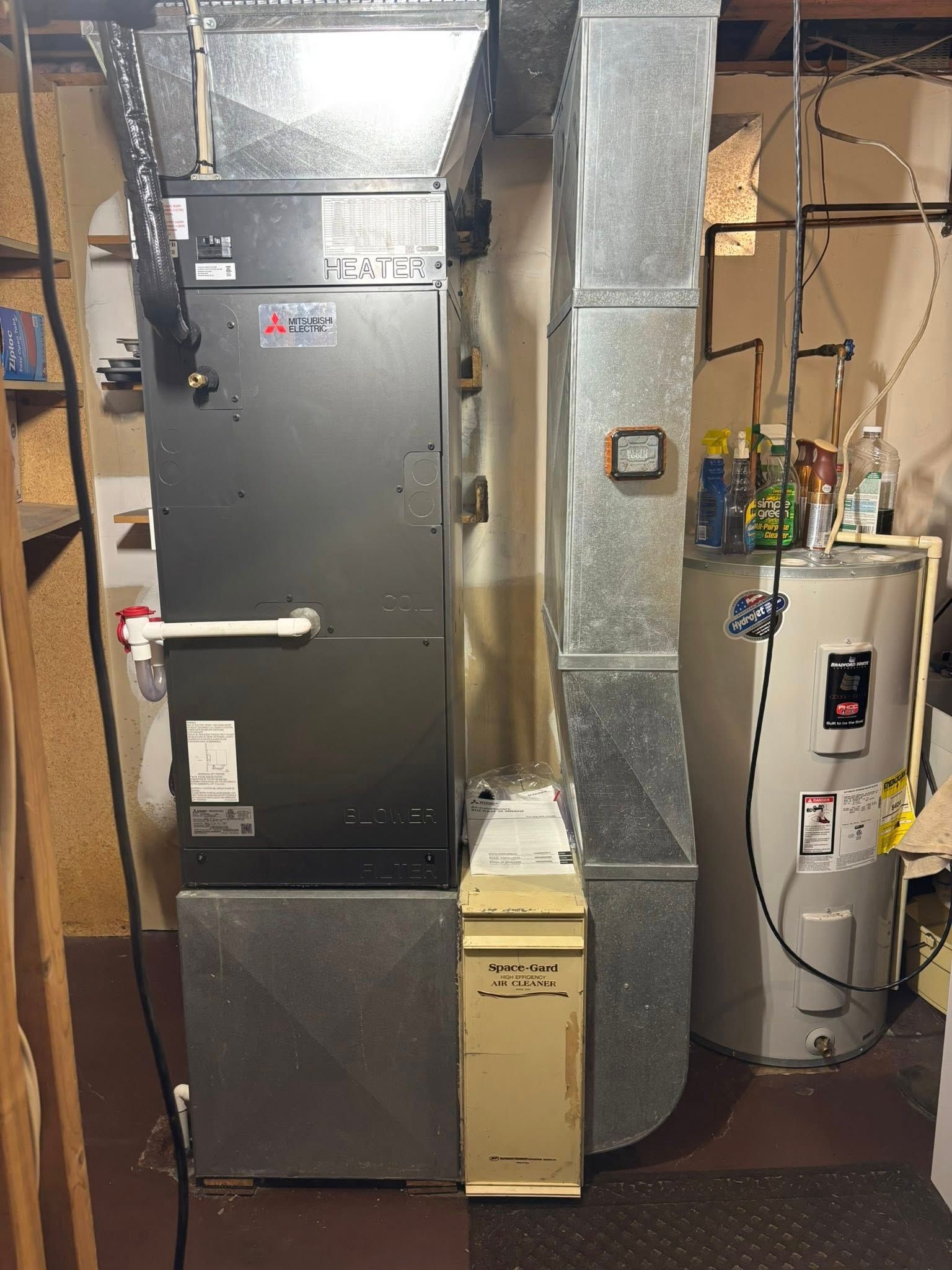 Furnace and water heater in a utility room. Metal ductwork and tanks visible.