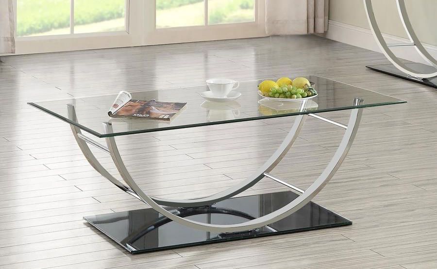 A glass coffee table with a bowl of fruit on it in a living room.