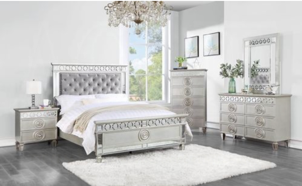 A bedroom with a bed , dresser , nightstand and mirror.