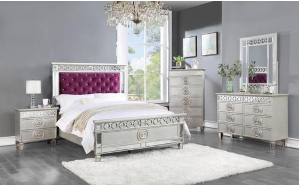A bedroom with a bed , dresser , nightstand , mirror and rug.