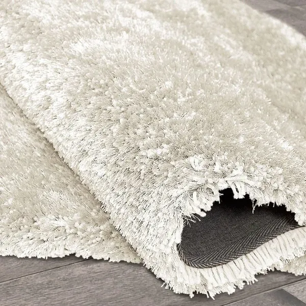 A white rug is laying on a wooden floor.