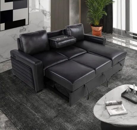 A black leather couch is sitting in a living room next to a coffee table
