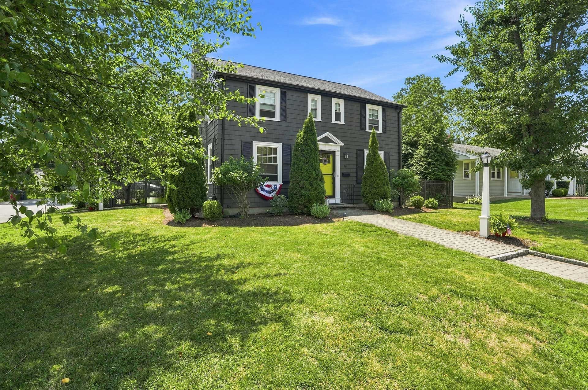 Dark gray house with white trim and a green lawn under sunny blue skies