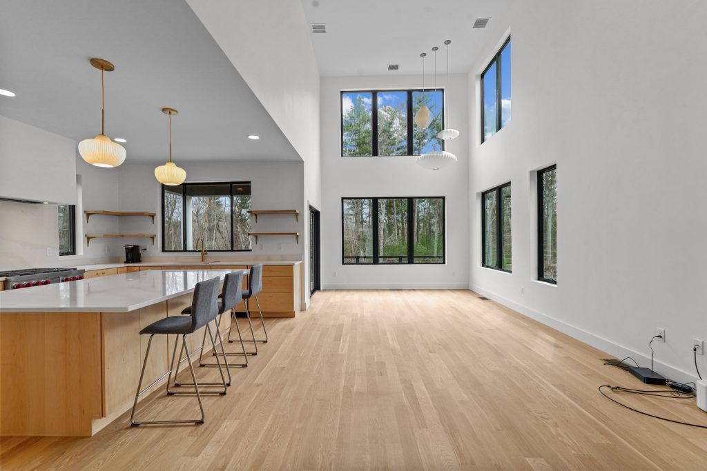 Spacious modern kitchen and living area with wood floors, large windows, and neutral colors.