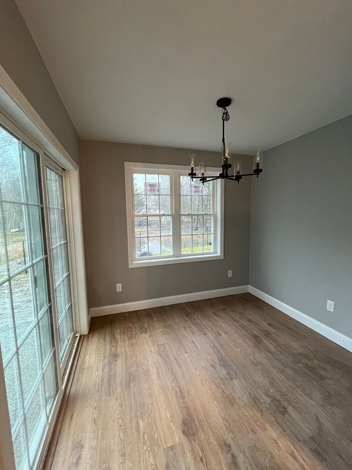 Dining room with hardwood floor, sliding glass door, window, chandelier, and gray walls.