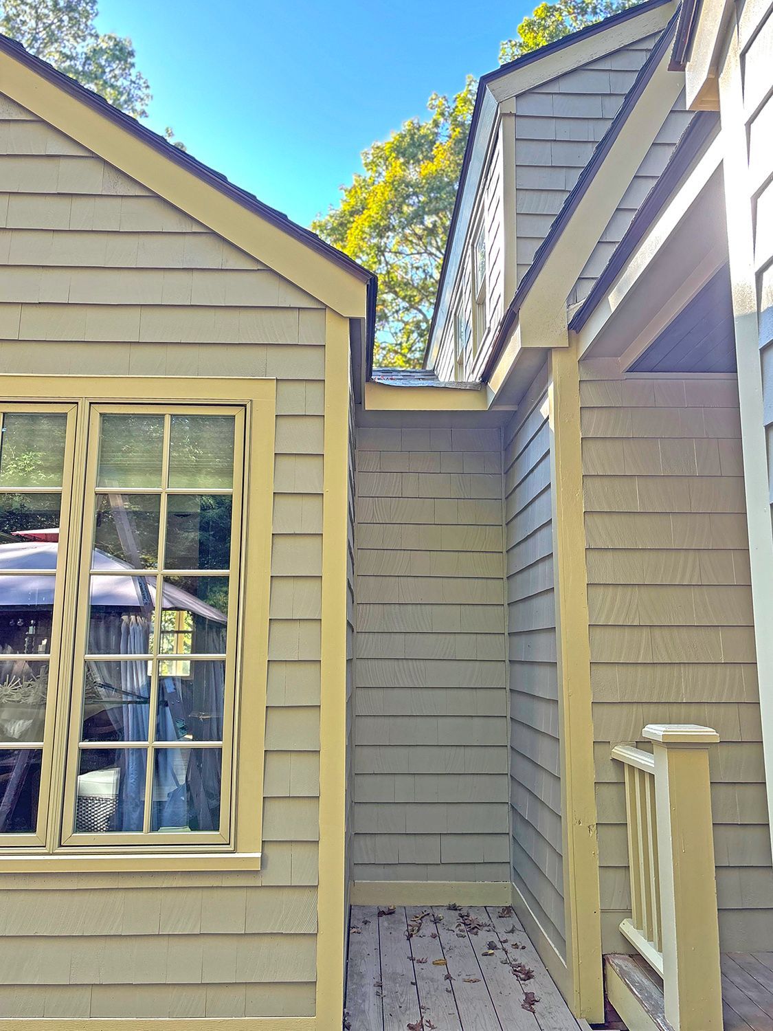 Exterior view of two connected buildings with gray siding and yellow trim.