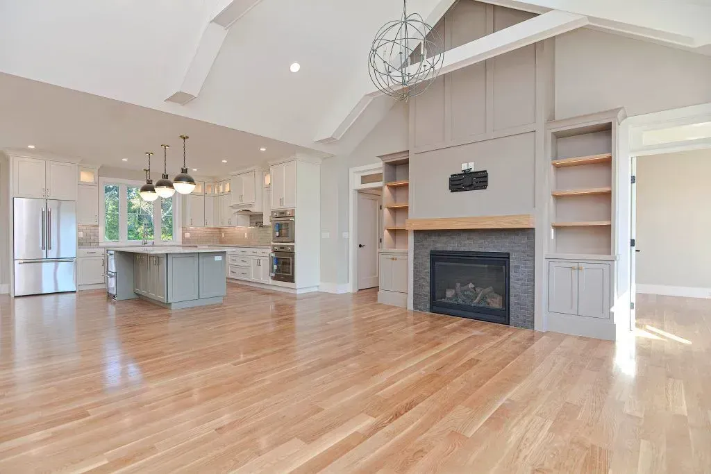 Spacious open-concept living space with hardwood floors, kitchen, fireplace, and built-in shelving.