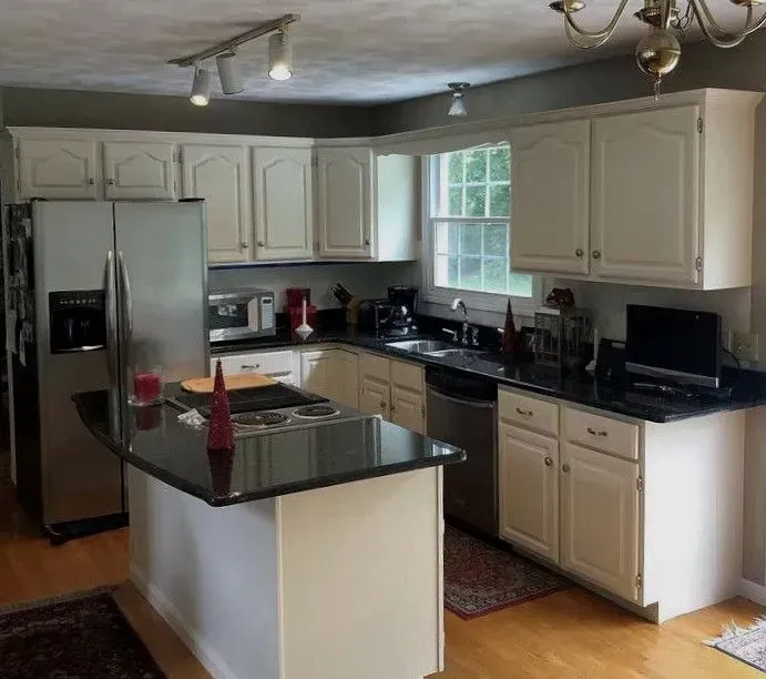 Kitchen with white cabinets, black countertops, and stainless steel appliances.