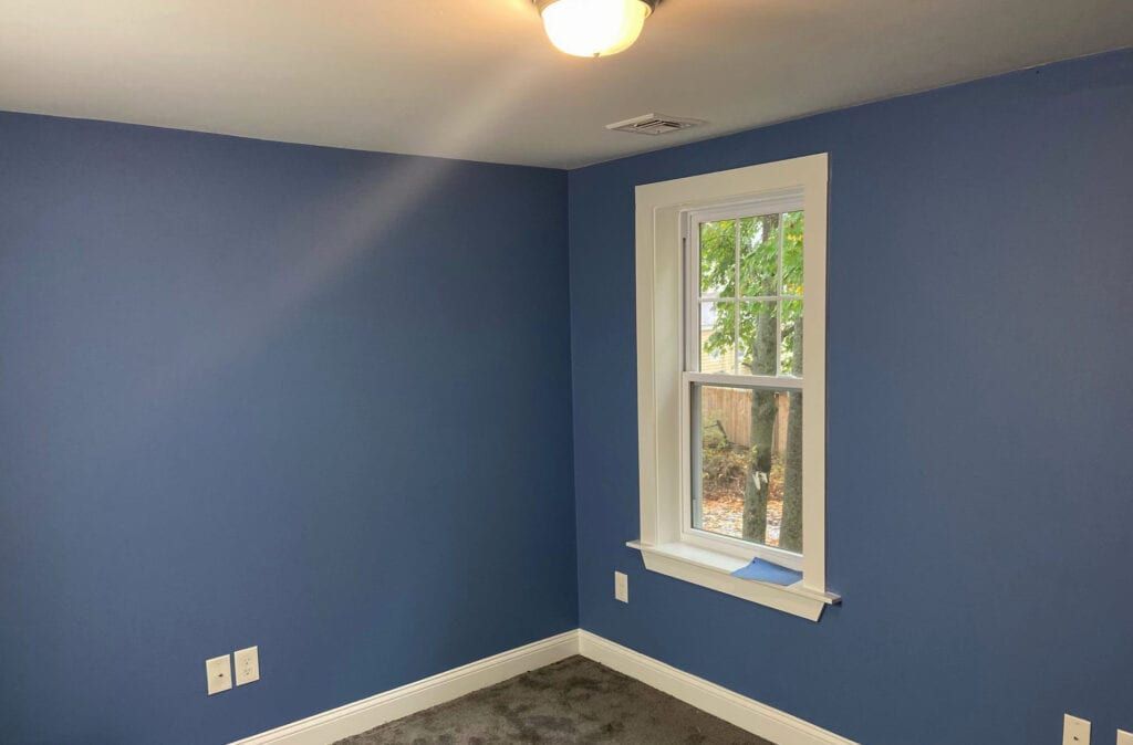 Blue painted room with white trim, window, and ceiling light.