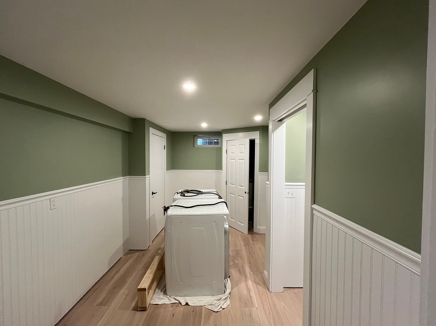 Green and white painted basement with a laundry appliance.