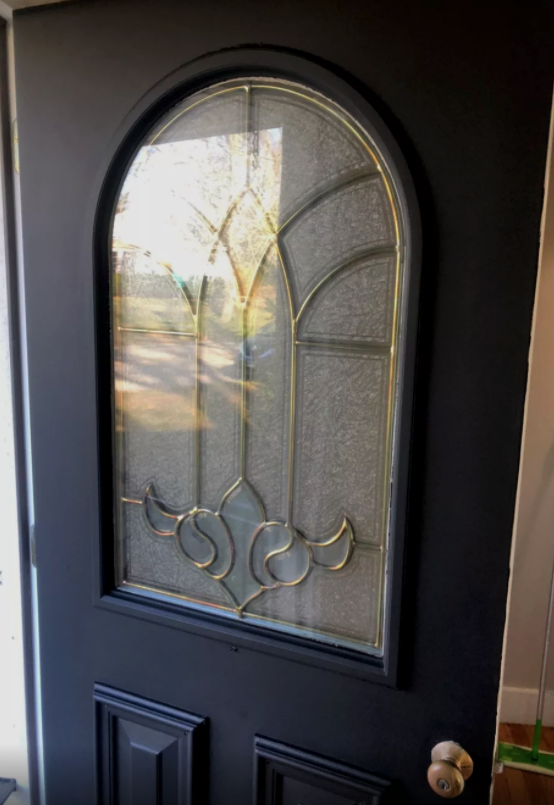 Black front door with arched stained glass window.