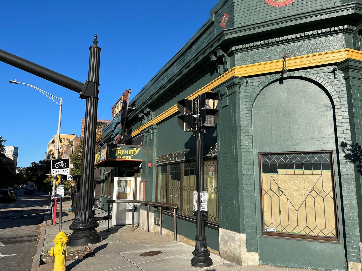 Green building with a yellow trim, black street lights, and yellow fire hydrant on a city street.