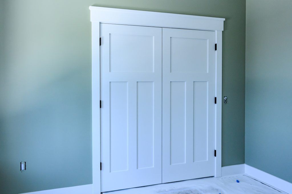 White paneled double doors with trim in a room with light green walls.