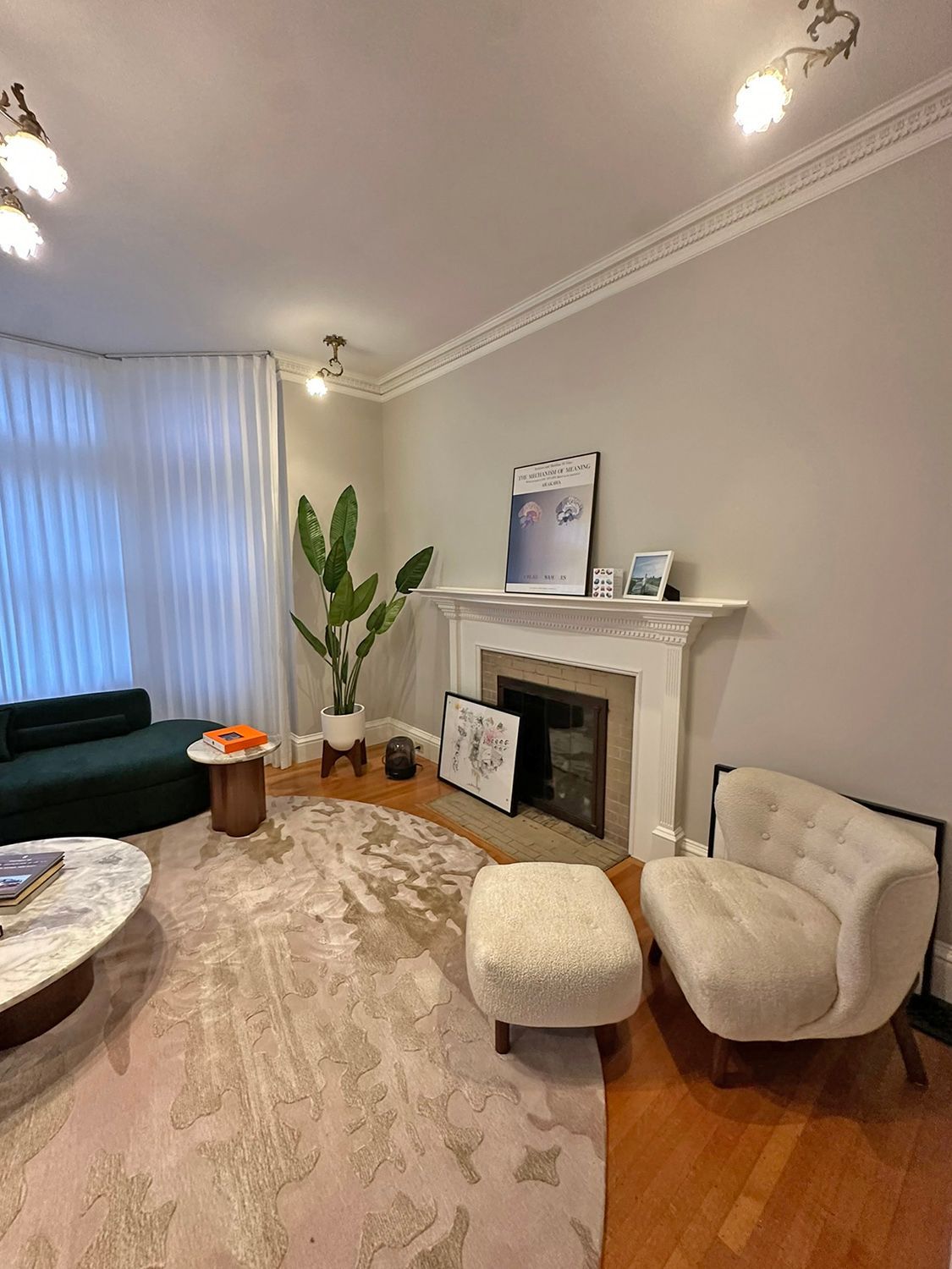 Living room with fireplace, green couch, white armchair, and patterned rug.