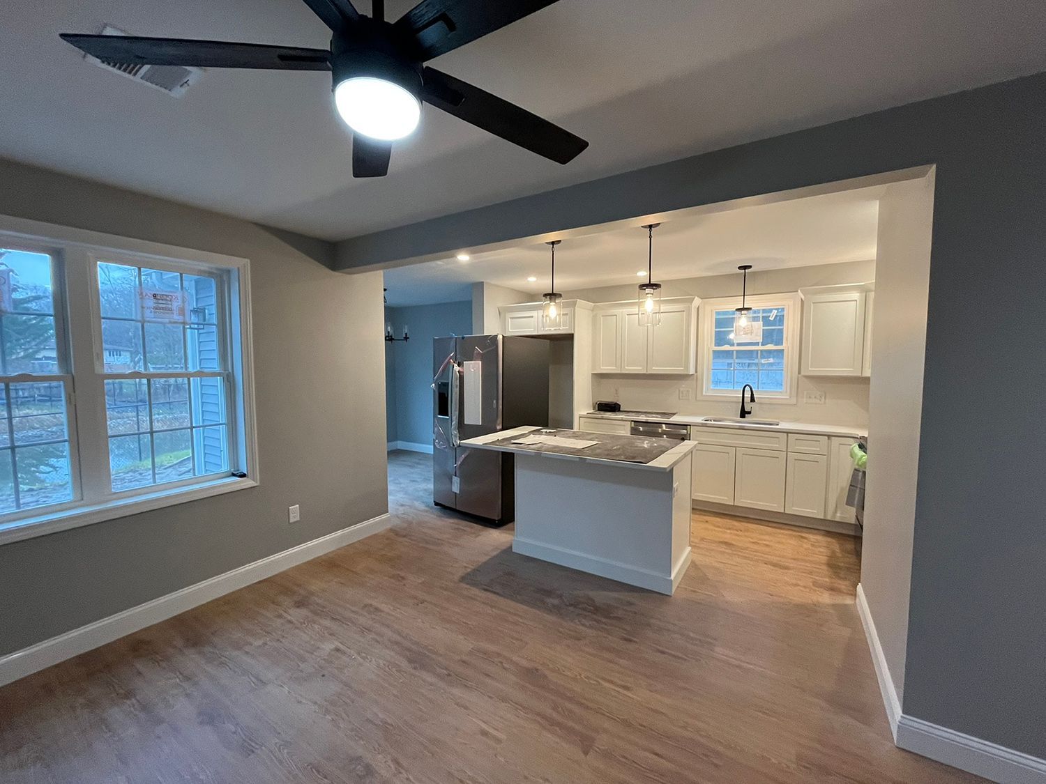 Open-concept kitchen and dining area with gray walls, light wood floors, and white cabinetry.
