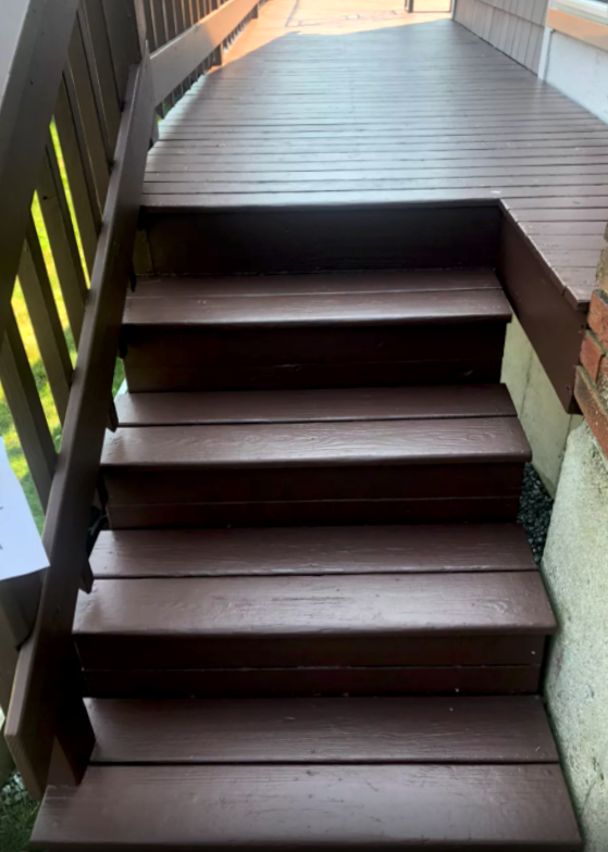 Wooden outdoor stairs leading up to a deck, painted brown.