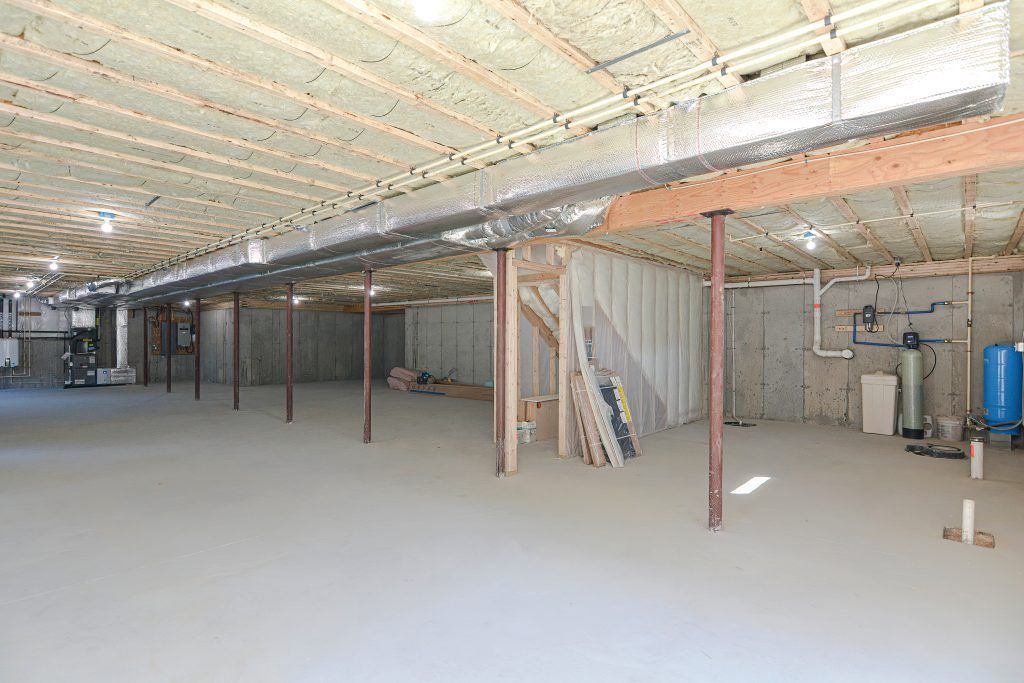 Empty basement with concrete floor, exposed ductwork, support beams, and unfinished walls.