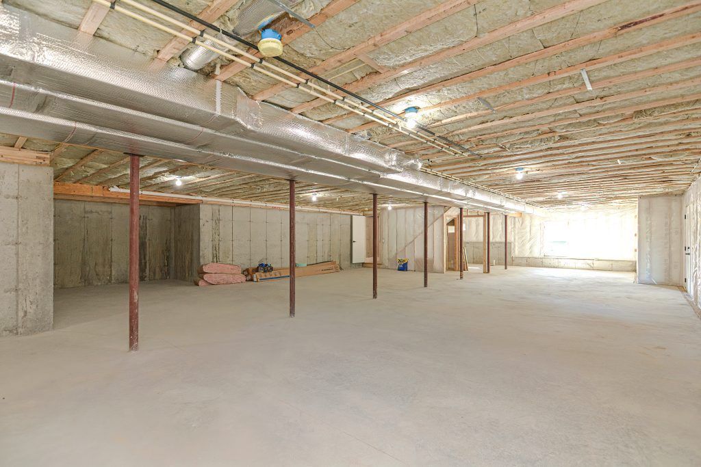 Spacious unfinished basement with concrete walls, support beams, and exposed ceiling insulation.