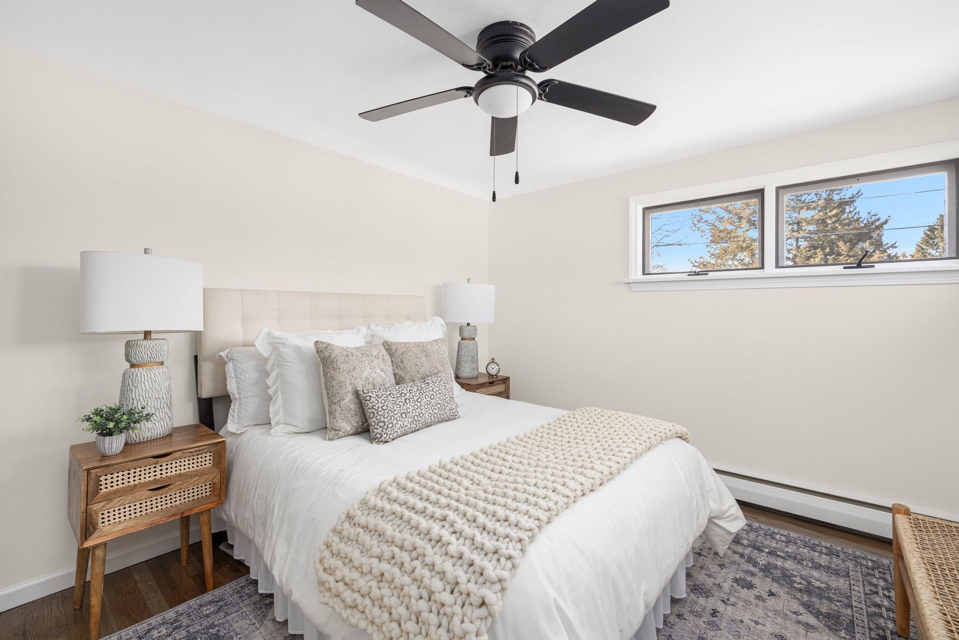 Bedroom with a bed, lamps, nightstands, rug, and a ceiling fan.