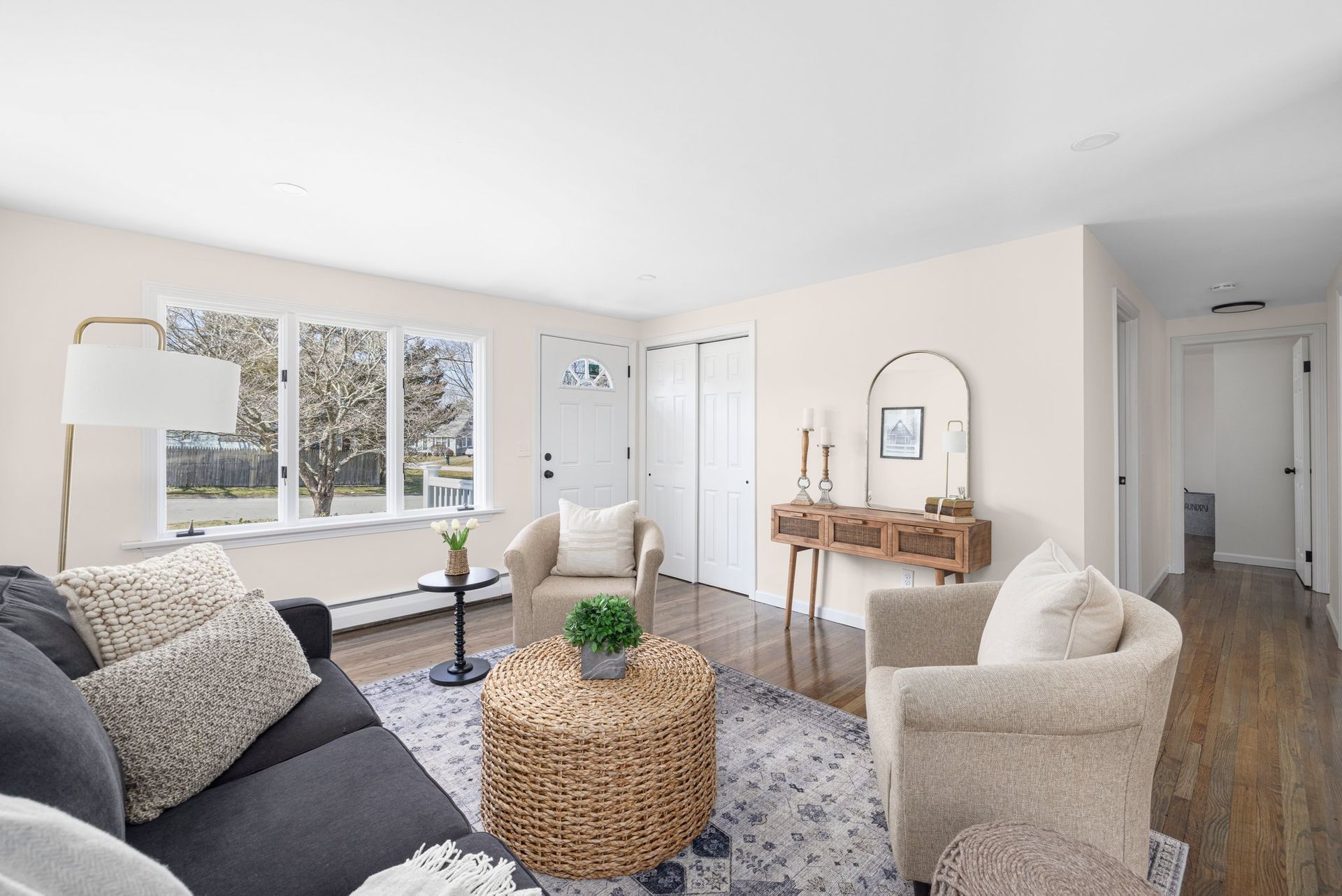 Living room with a dark gray sofa, tan armchairs, and a woven coffee table.