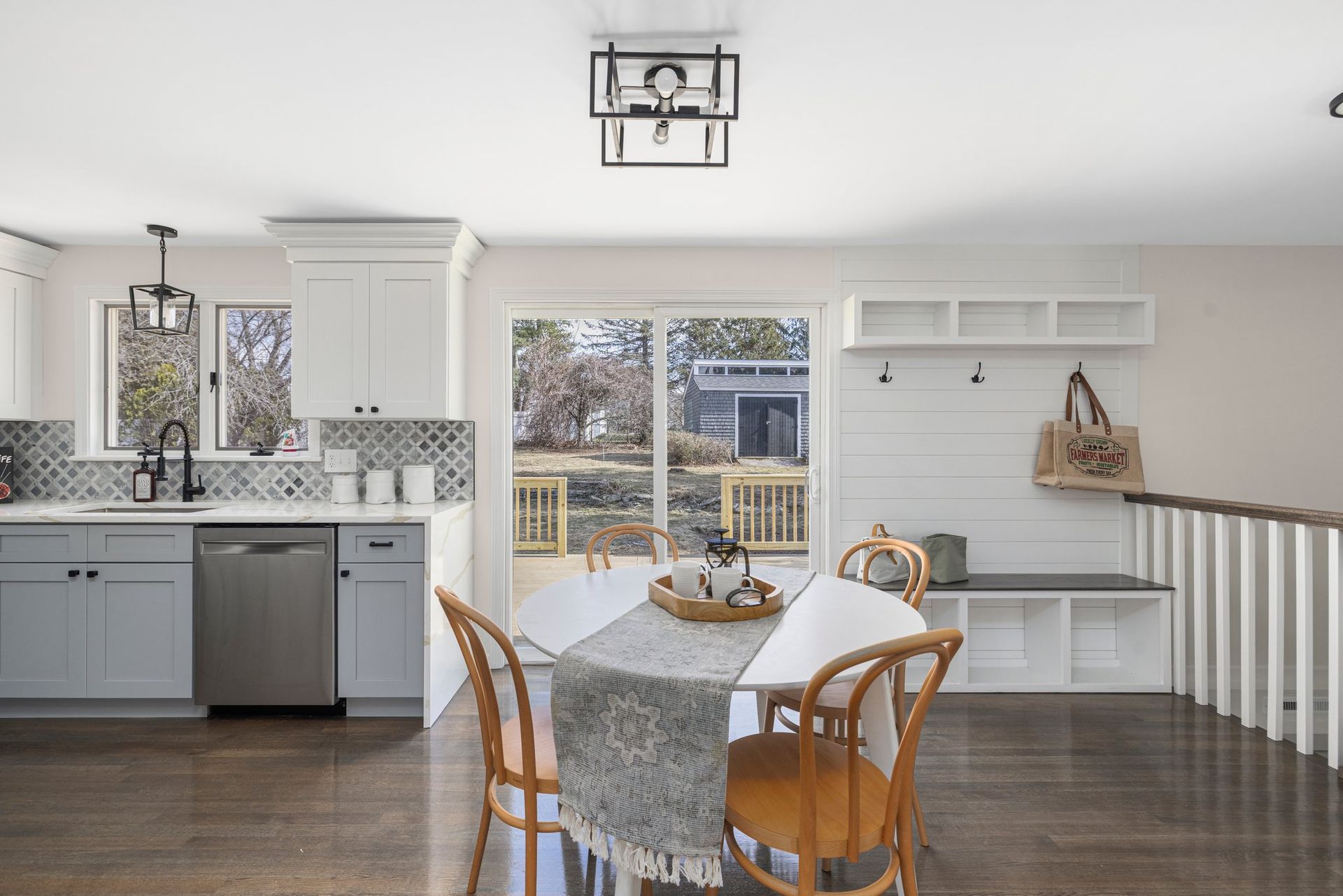 Kitchen and dining area with gray and white cabinets, round table, sliding doors to a deck.