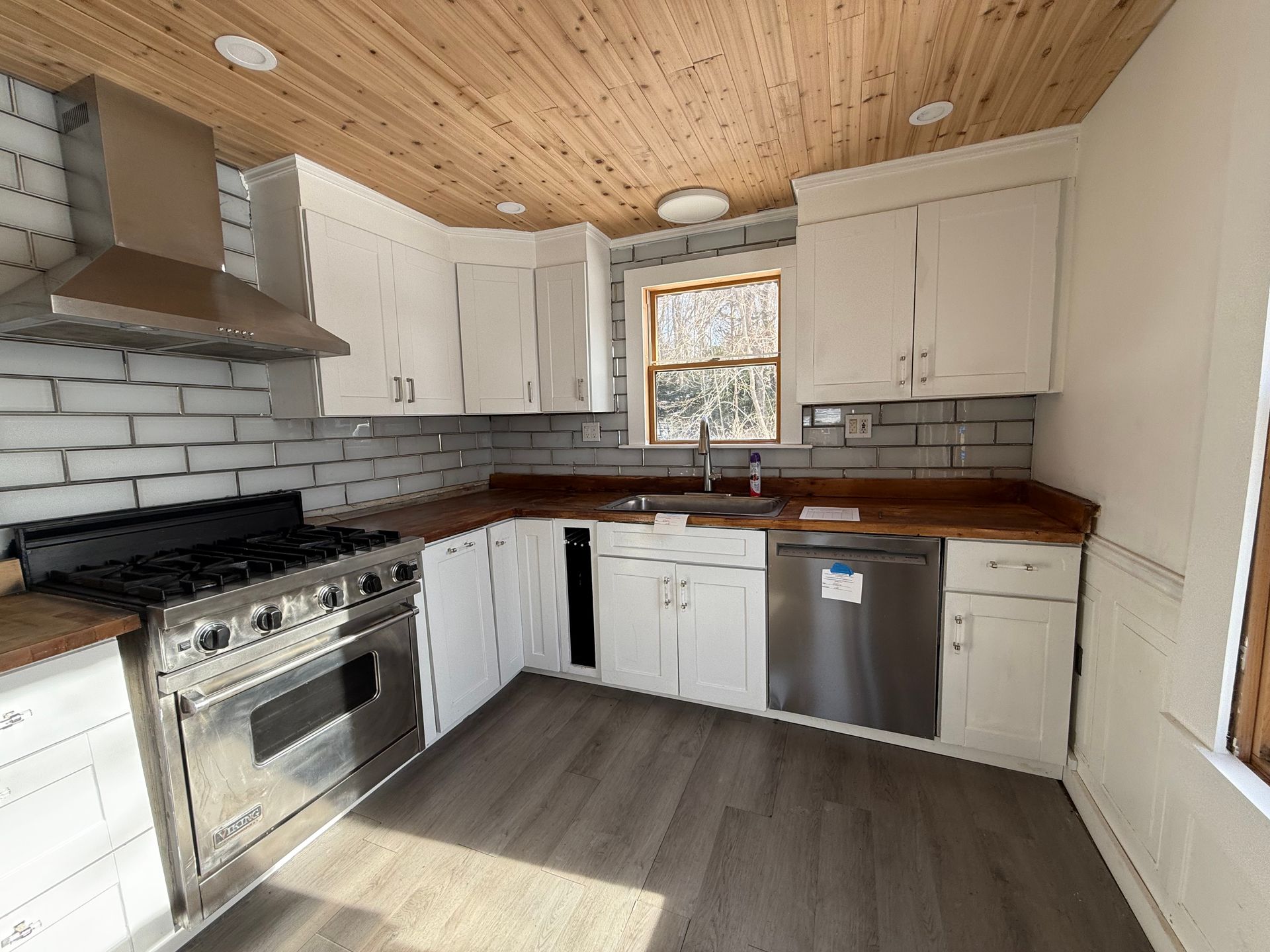 Kitchen with white cabinets, stainless steel appliances, wood countertops, and wood ceiling.
