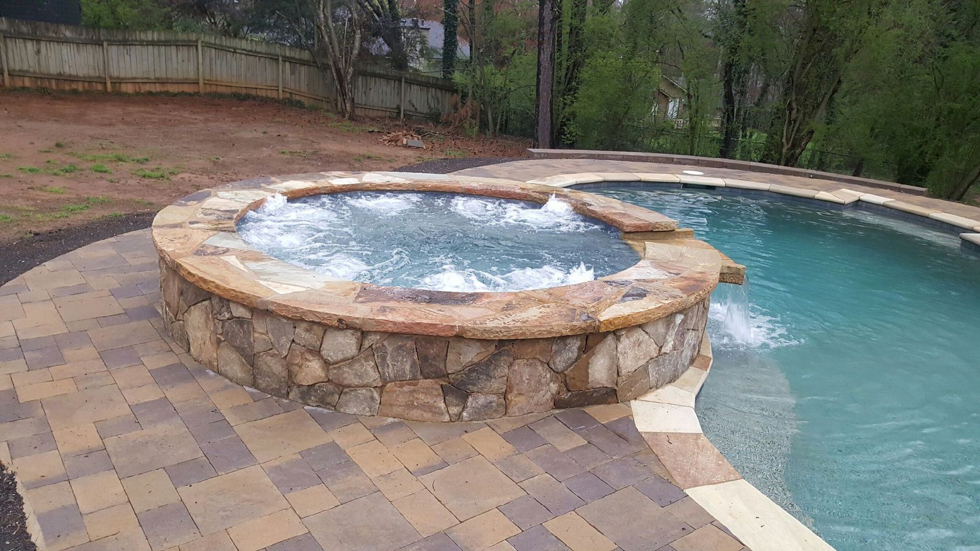 A large swimming pool with a hot tub in the middle of it.