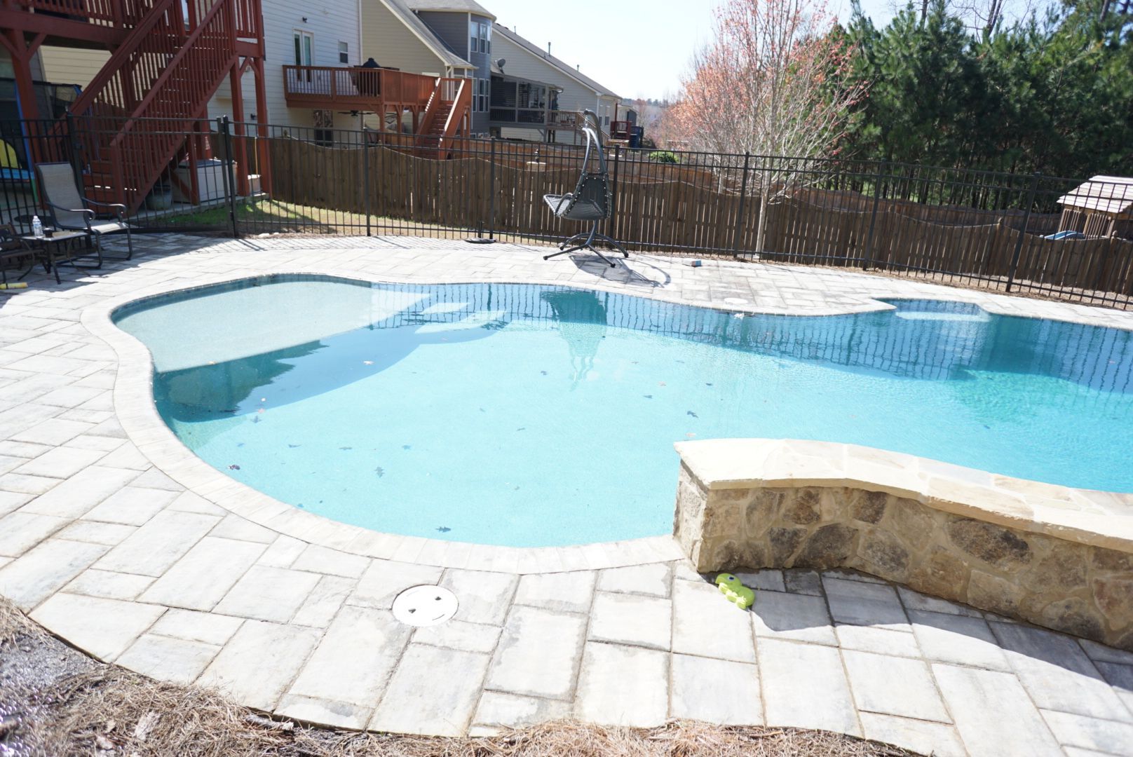 There is a large swimming pool in the backyard of a house.