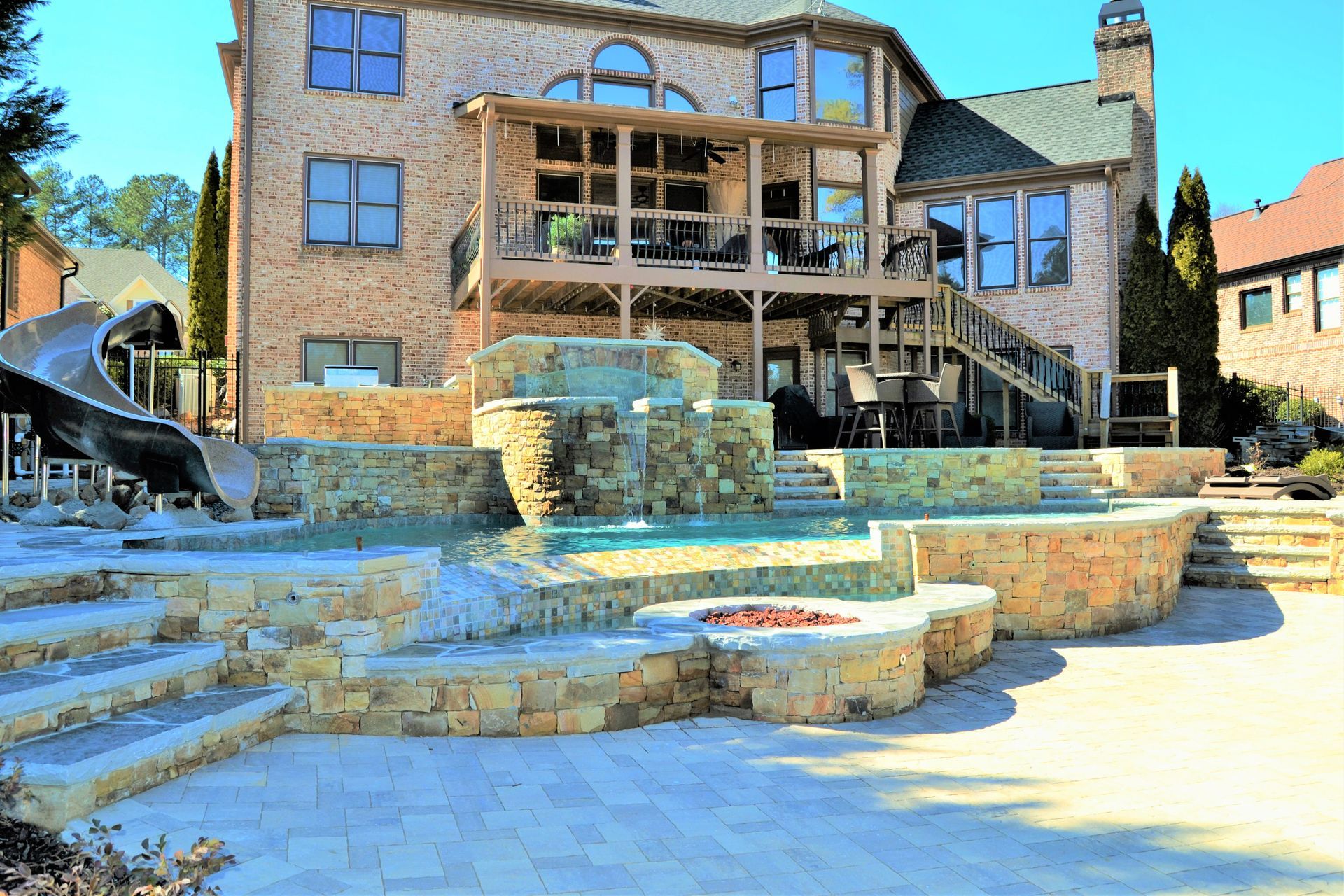 A large brick house with a slide and a pool in front of it.
