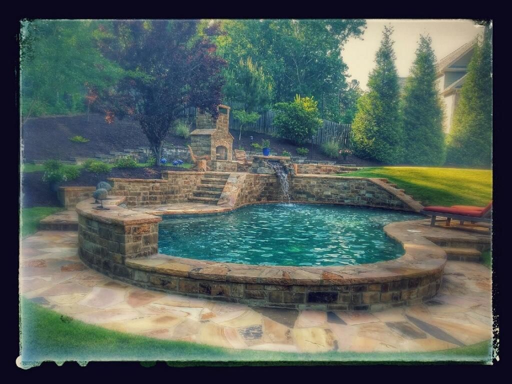 A large swimming pool surrounded by stone walls in a backyard